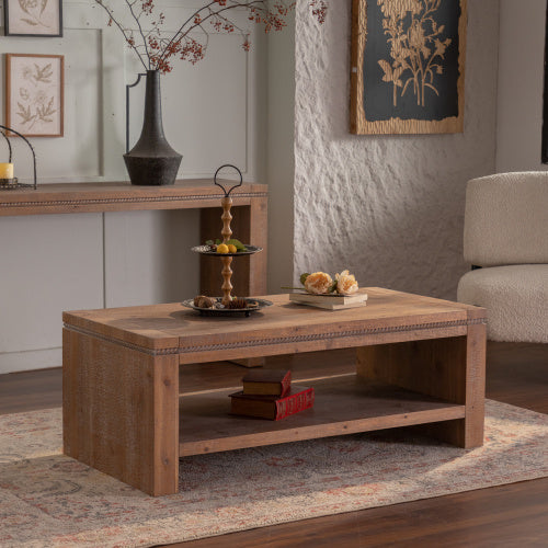 Wooden coffee table in a living room setting with decorative items and a sofa.