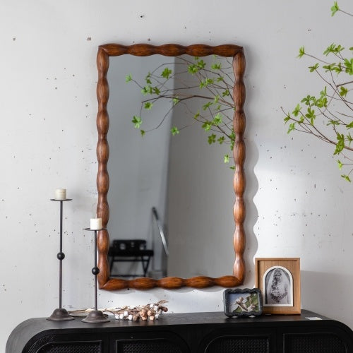 Wooden-framed mirror on a wall with decorative items below